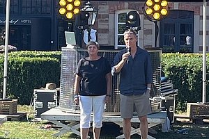 Zwei Personen stehen auf einer Wiese vor einem DJ-Stand mit dem Schriftzug 'DJ Dirk' auf dem Zeltdach