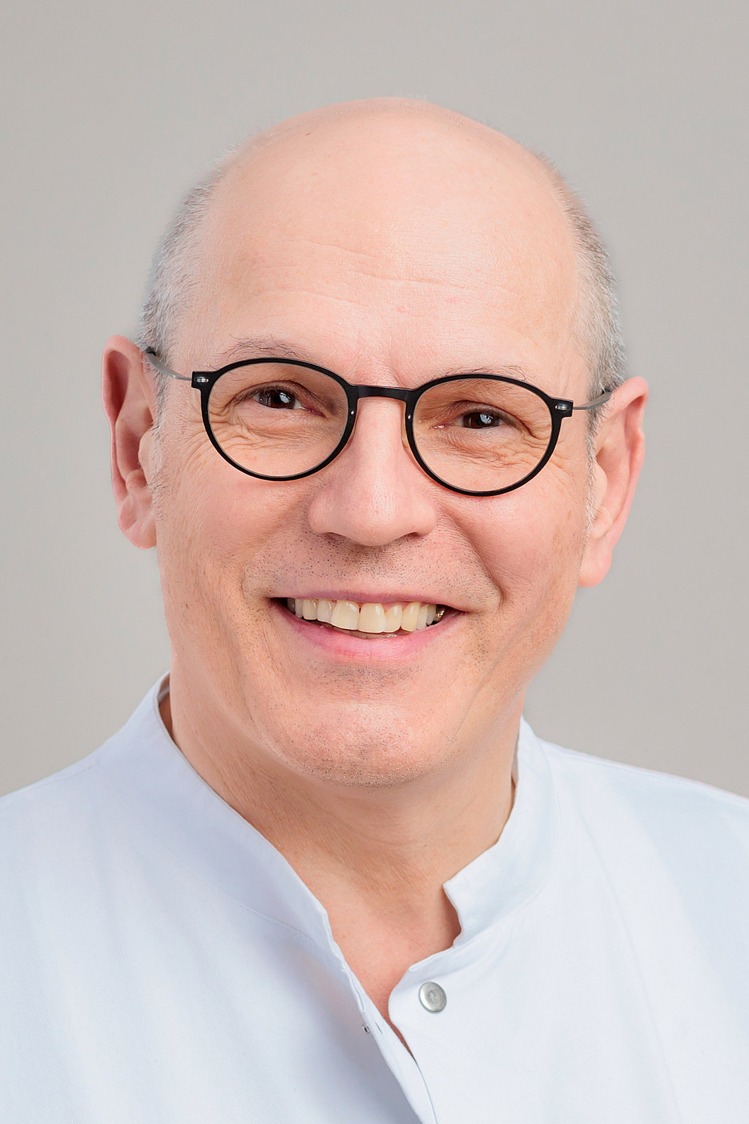 Dr. Eric-Thorsten Steinheim in dunklem Anzug, hellblauem Hemd und dunkelroter Krawatte mit Muster.