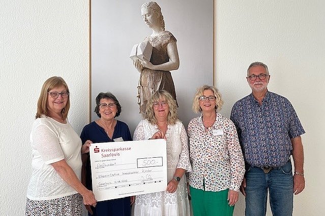 Fünf Personen stehen vor einer Wand mit einer Skulptur eines Frauenbildes, eine Person hält einen großen Scheck über 500 Euro von der Kreissparkasse Saerbeck.