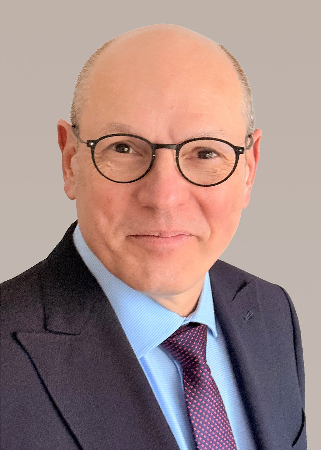 Dr. Eric-Thorsten Steinheim in dunklem Anzug, hellblauem Hemd und dunkelroter Krawatte mit Muster.