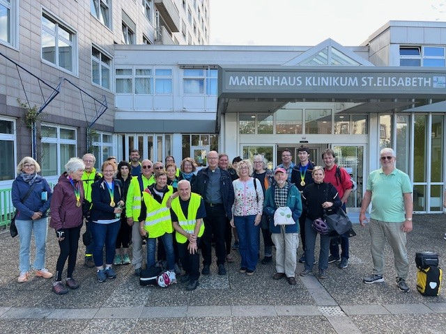 Gruppe von etwa 25 Personen, viele mit Fahrradhelmen und reflektierenden Westen, vor dem Eingang des Marienhaus Klinikums St. Elisabeth.